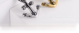 Detailed macro view of retro stainless steel anchor pendants with skull embossed patterns