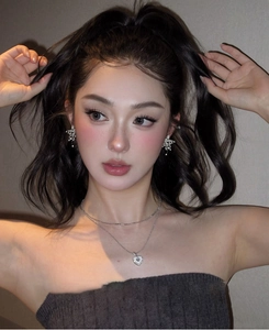 Detail view of model wearing a layered silver star necklace and heart earrings set