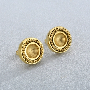 Pair of gold circular stud earrings with rope textured edges on a grey surface
