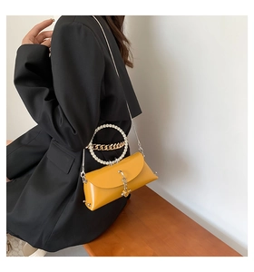Detail of a yellow jelly bag with rhinestone ring handle and metal chain on a model