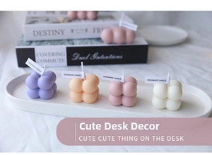 Detail of four handmade bubble cube scented candles in pastel colors on a tray