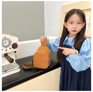 Detail of plush brown children's chest bag with metal zipper and soft fleece texture