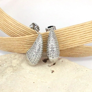 Detailed view of teardrop earrings with shimmering zircons on a natural stone base