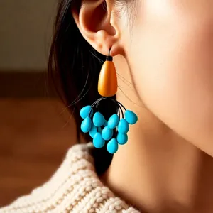 Vintage ethnic drop earrings with orange and sky blue beads worn by a model