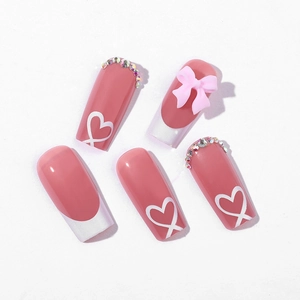 Pink French fake nails with white hearts, rhinestones, and 3D bowknot decor