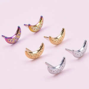 Macro detail of crescent moon earrings in iridescent purple, gold, and silver finishes