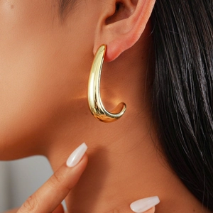 Close-up of elegant gold droplet earring worn by a model for a modern minimalist look