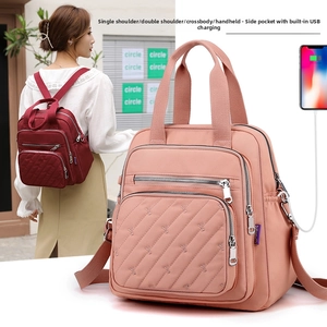 Detail of pink nylon backpack featuring an external USB charging port and quilted pocket