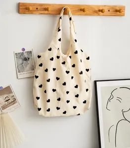 Strukturierte Canvas-Tasche mit schwarzem Herzmuster an einem Holzregal hängend