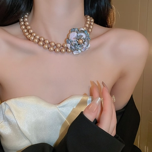 Close-up of a double-layer pearl necklace with a vintage floral enamel pendant and crystals