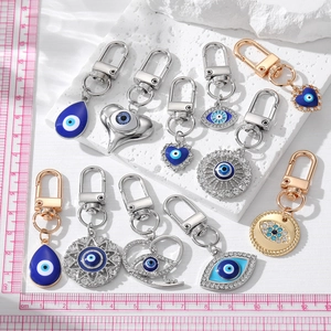 Various evil eye keychains in heart and teardrop shapes with blue enamel and gold finish