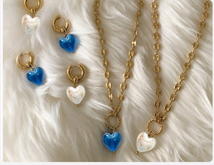Detailed close-up of golden pig-nose chain necklaces and heart-shaped glass pendants on white fur