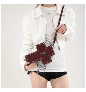 Detail of gothic dark red cross bag with silver studs and skull chain worn by model
