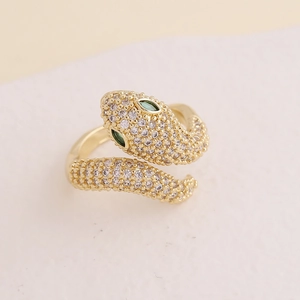 Macro shot of gold snake-shaped ring featuring sparkling white and green zircon stones