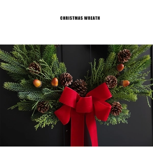 Christmas wreath with natural pine cones, green needles and a large red velvet bow on top