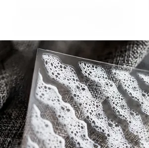 Detail of white foam and wave texture nail stickers on a translucent adhesive film