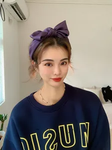 Detail view of a large purple satin bow headband with a wide-brimmed aesthetic design