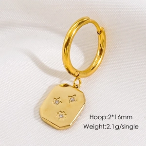 Detail of gold hoop earring with star-patterned octagonal charm and zircon inlay