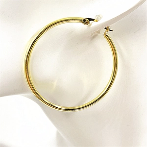 Macro shot of minimalist gold plated hoop earring on white ear model with glossy finish