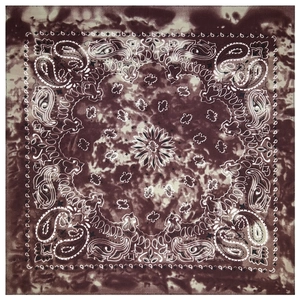 Detail of dark brown tie-dye bandana featuring classic white paisley patterns on fabric