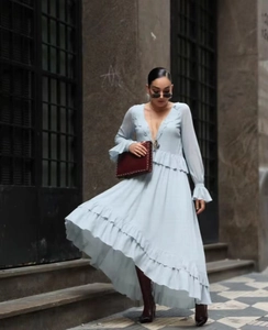 Detail of light blue V-neck long sleeve dress with ruffles and burgundy studded handbag