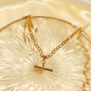 Close-up of gold stainless steel OT buckle necklace with tube pendant on silk