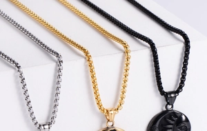 Detailed view of silver, gold and black titanium steel chain necklaces on geometric stairs