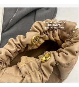 Close-up of golden magnetic closure and soft pleated leather on beige bucket bag