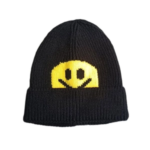 Detail of black knitted beanie with yellow smiley face embroidery and ribbed texture