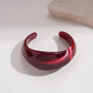 Macro shot of minimalist burgundy acrylic marble cuff bracelet with white swirl texture
