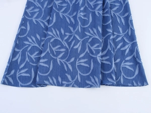 Detail of blue denim fabric with embossed leaf pattern and high-quality jacquard embroidery