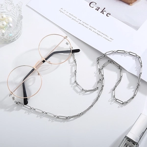 Détail de lunettes rondes avec une chaîne en métal argenté sur un fond stylisé chic