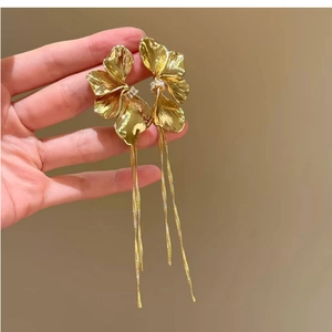 Macro shot of gold metal flower earrings with crystal center and long hanging tassels