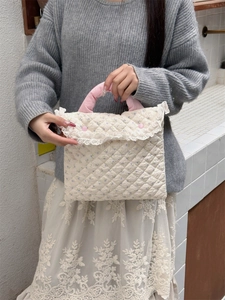 Close-up of quilted laptop bag with purple floral pattern, lace trim, and pink satin handles