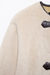 Dettaglio cappotto in pelliccia sintetica con finiture in pelle e chiusura a alamaro