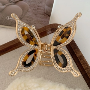 Elegant gold butterfly hair claw clip with rhinestones and tortoiseshell pattern on wood