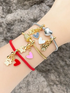 Gros plan de charms en émail en forme de cœur et pendentifs d'os sur des chaînes