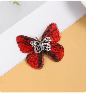 Vue détaillée montrant la broderie et l'épingle de sûreté argentée de la broche papillon