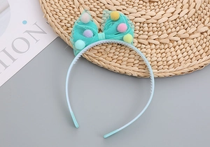 Detailed view of mint green mesh bow headband with colorful pompoms and anti-slip teeth