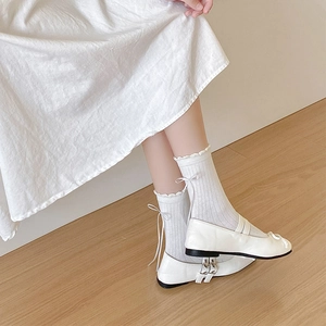 Detail of white rib-knit socks featuring delicate bow ties and lettuce edge cuffs