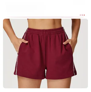 Dettaglio dei pantaloncini bordeaux a vita alta con tasche laterali e strisce bianche laterali