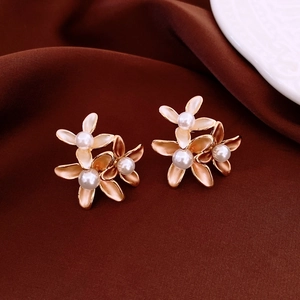 Macro detail of elegant floral pearl earrings on luxurious deep red silk background