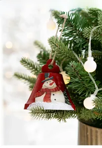 Detailed view of red metal Christmas bell featuring hand-painted snowman on a tree branch
