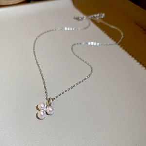 Macro shot of clover shaped pearl pendant with zircon inlay on a silver chain