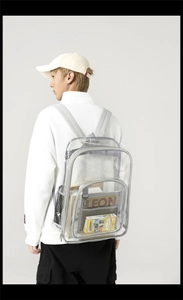 Detail view of transparent PVC backpack with grey straps and side mesh pocket on a model