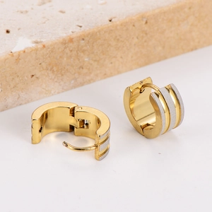 Three-layer two-tone mixed gold and silver huggie hoop earrings on a textured stone base