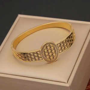 Close-up of gold hollow leaf bracelet featuring intricate carved metal texture details