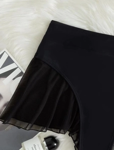 Close-up of black mesh ruffle detail and sheer splicing on elastic bikini bottoms