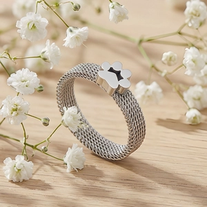 Detail of mesh band ring featuring a cute paw print design on a rustic wooden table