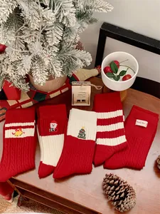 Détail de chaussettes de Noël rouges et blanches avec broderie sur fond festif en bois